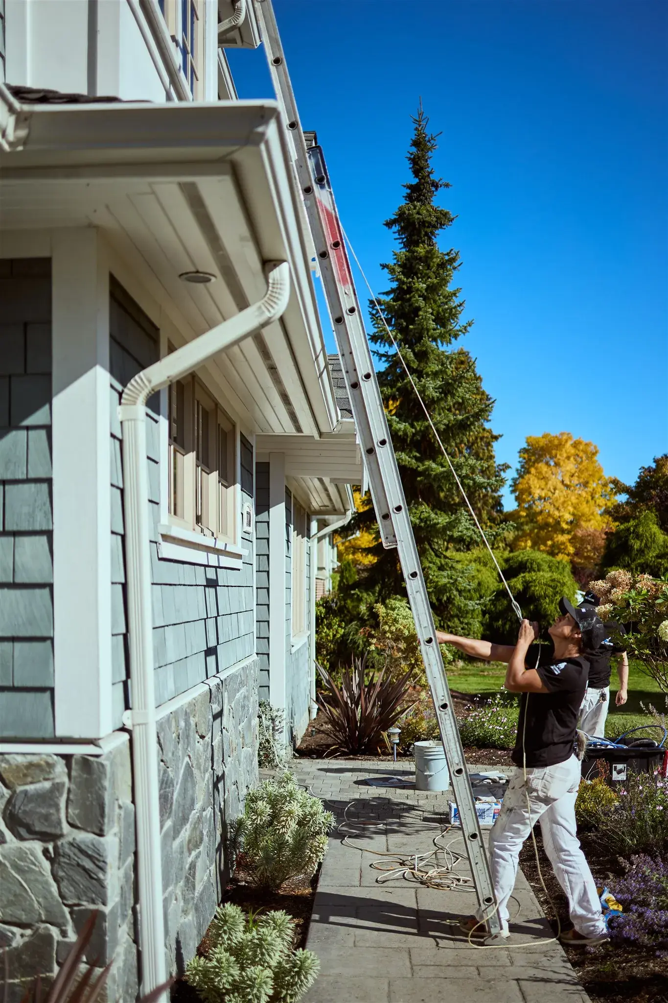 Crew working from ladders on a shingled exterior