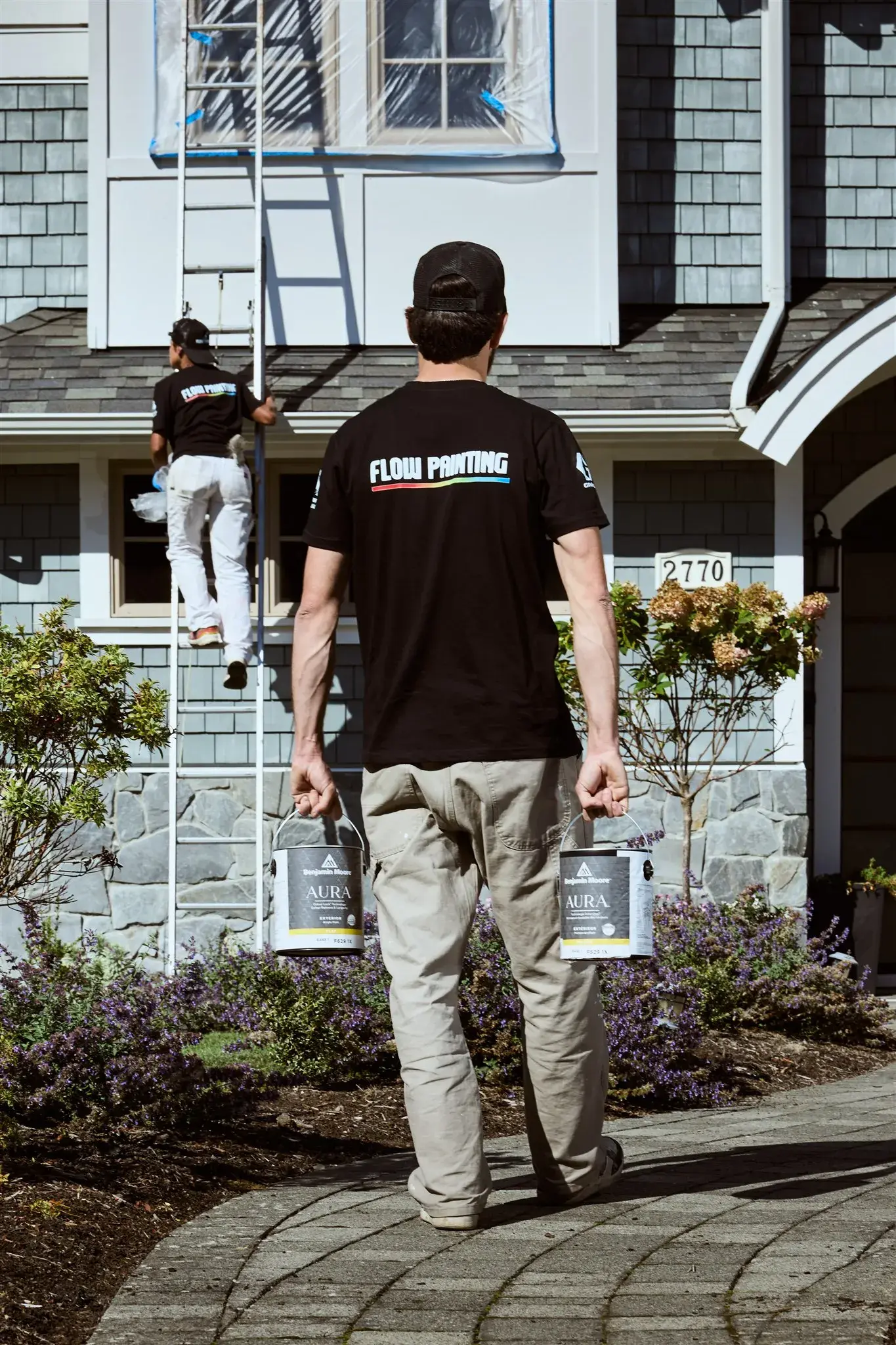 Flow Painting crew member carrying paint to an exterior job