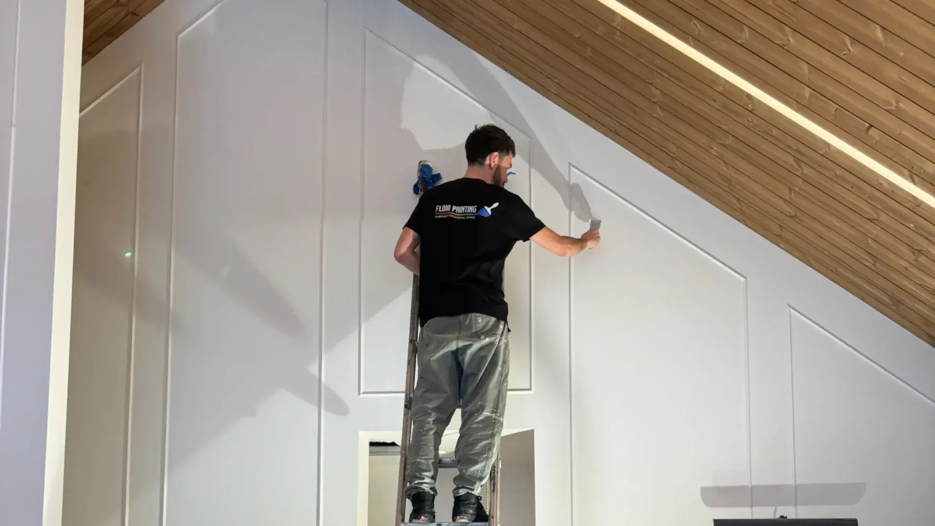 Interior painting — crew finishing a tall feature wall